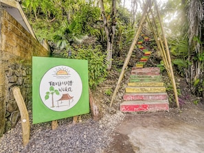 A staircase with a green signboard and a wooden structure beside it. - OYO Homes 91118 Homesstay Desa Wisata Budo (Wori)