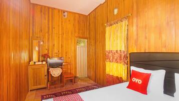 A wooden-paneled room with a bed, a desk, a chair, and a window with curtains.