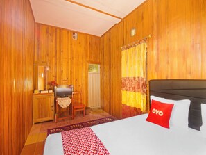 A wooden-paneled room with a bed, a desk, a chair, and a window with curtains. - OYO Homes 91118 Homesstay Desa Wisata Budo (Wori)