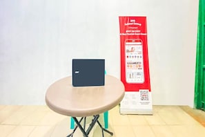 Un ordinateur portable est posé sur une petite table, avec un panneau rouge en arrière-plan.