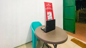 A small table with a laptop, a turquoise chair, and a red sign on the wall. - Spot ON 91227 Al Bayt Syariah Guest House (Kupang)