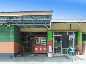 A building with a covered entrance, a visible storefront, and outdoor seating.