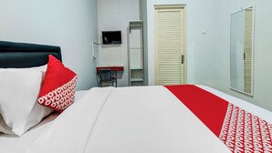 A hotel room with a bed, a TV mounted on the wall, a wardrobe, and a mirror. - OYO Flagship 90983 Harmony Easy Stay (Depok)