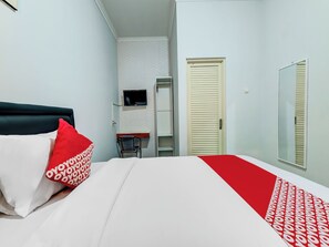A hotel room with a bed, a TV mounted on the wall, a wardrobe, and a mirror. - OYO Flagship 90983 Harmony Easy Stay (Depok)