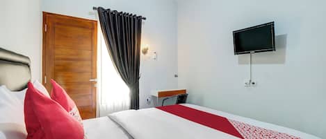 Una habitación de hotel con una cama, televisor y ventana con cortinas.