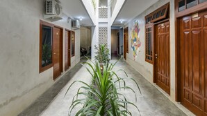 A corridor with wooden doors, a central air conditioning unit, and a ceiling with a skylight. - OYO Flagship 90983 Harmony Easy Stay (Depok)