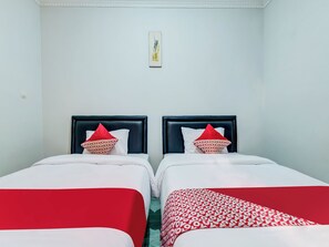 Ein Hotelzimmer mit zwei Betten, jeweils mit einer roten und weißen Bettdecke und passenden Kissen.