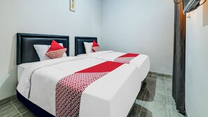 A hotel room with a bed, two pillows, a red and white patterned bedspread, a wall-mounted TV, and a ceiling light. - OYO Flagship 90983 Harmony Easy Stay (Depok)
