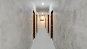 A hallway with marble walls and wooden doors, leading to a room with a sign above the door. - OYO Flagship 90983 Harmony Easy Stay (Depok)