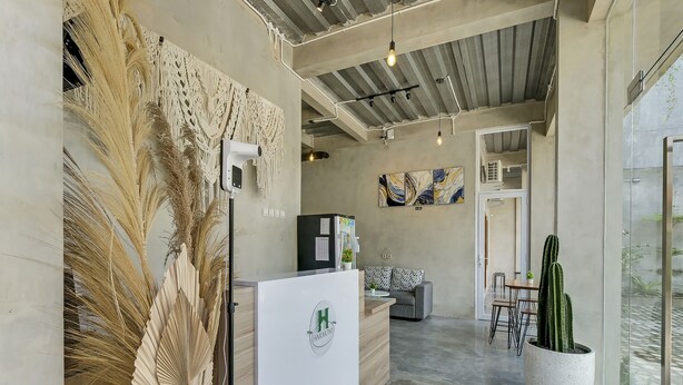 A reception area with a modern design, including a reception desk, a sofa, and a cactus plant. - OYO Flagship 90983 Harmony Easy Stay (Depok)