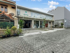 Ein Hotel mit moderner Fassade, gefliestem Eingangsbereich und Pflanzkübeln.