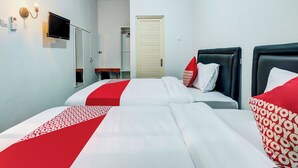 A hotel room with two beds, a TV, a desk, and a wardrobe. - OYO Flagship 90983 Harmony Easy Stay (Depok)