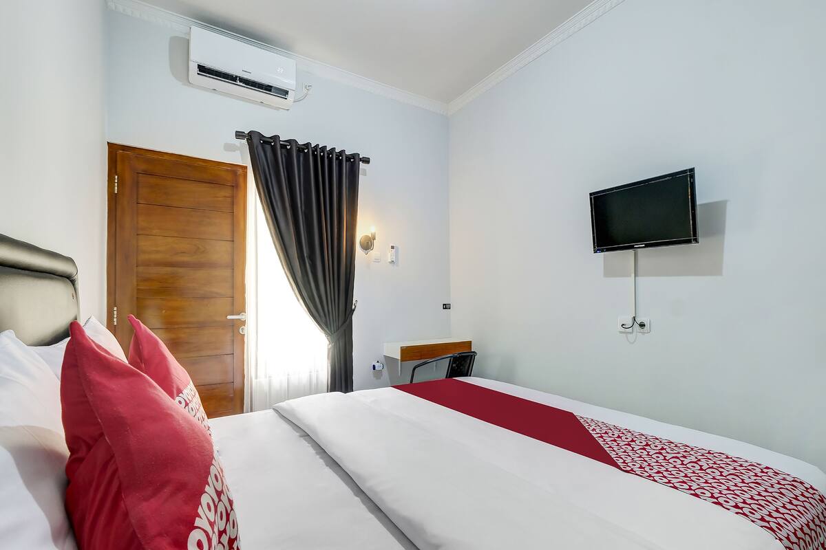 Ein Hotelzimmer mit Bett, Fernseher und einem Fenster mit Vorhängen.