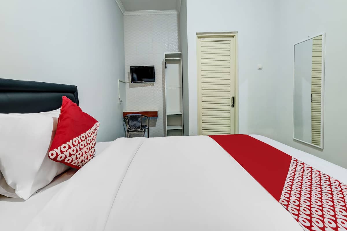 Ein Hotelzimmer mit Bett, Wandfernseher, Kleiderschrank und Spiegel.