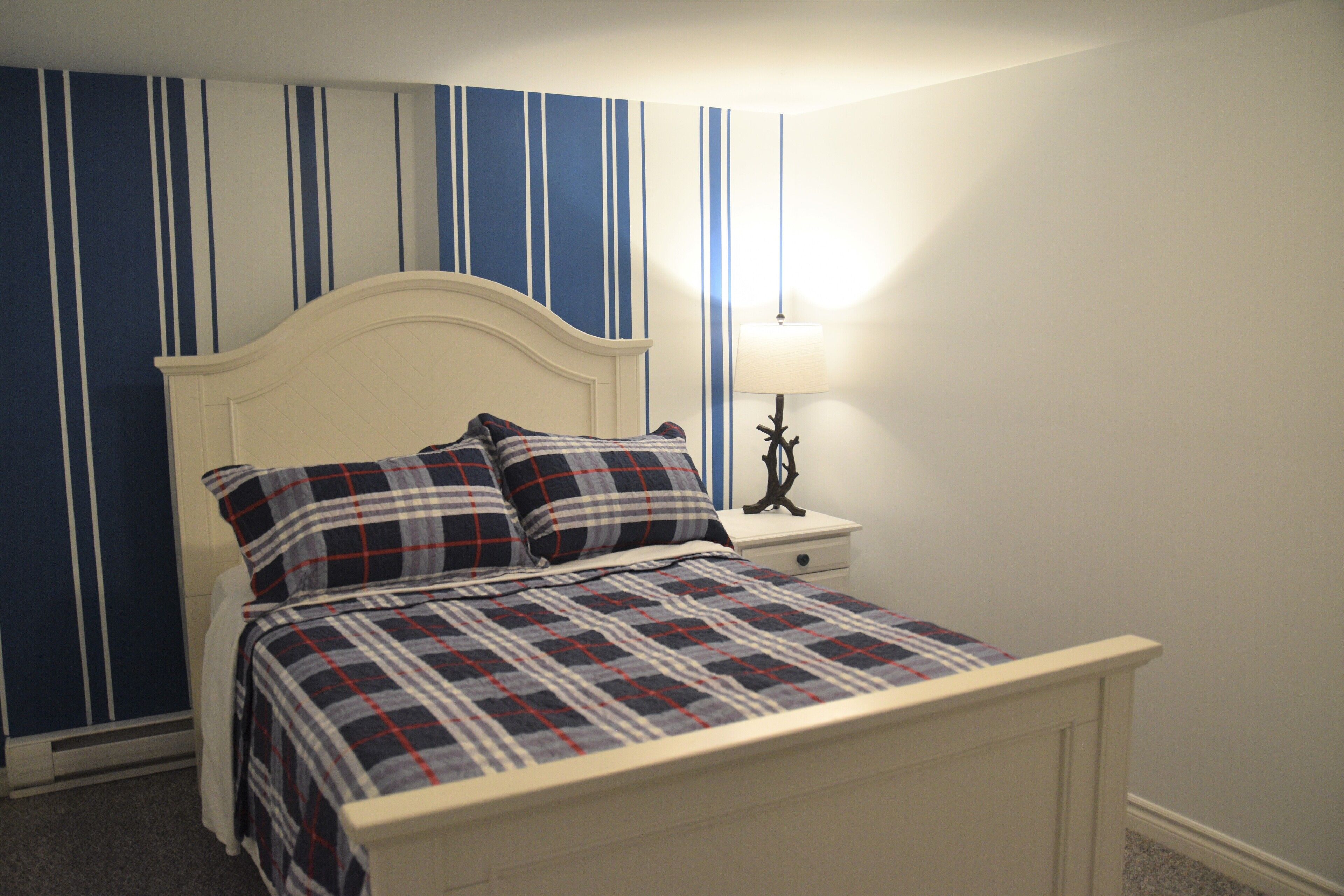 A bedroom with a bed, nightstand, and lamp.