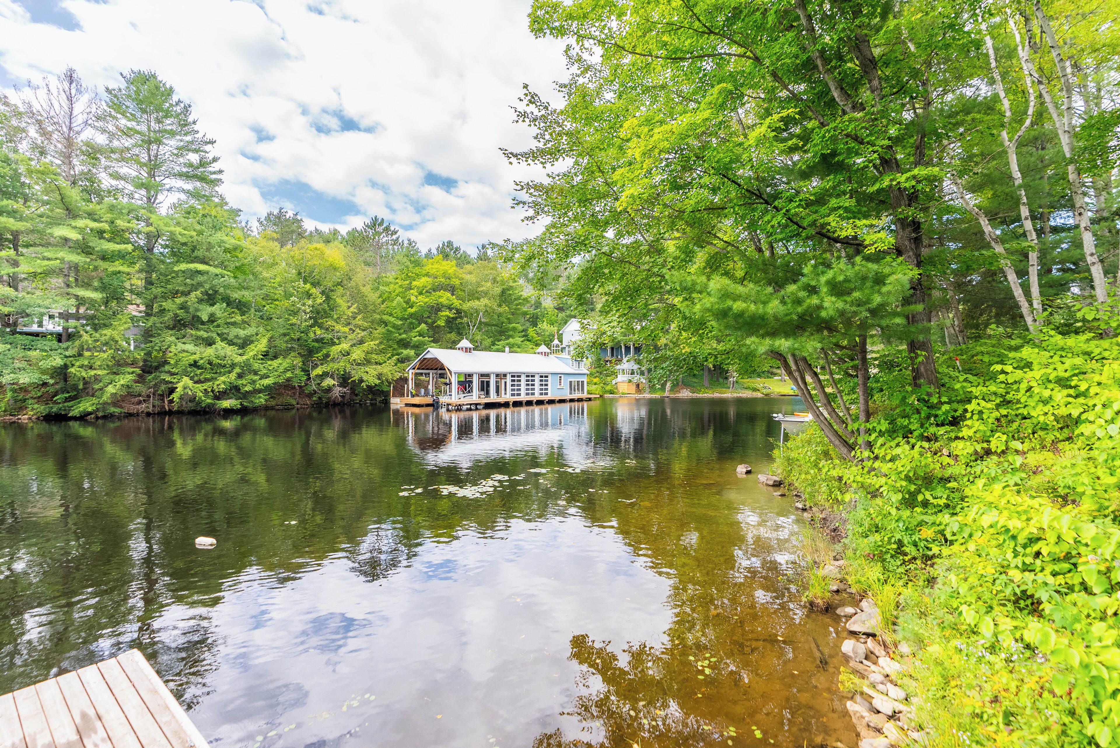 A lakeside cabin with a dock, surrounded by dense greenery and trees.