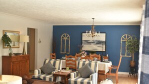 A dining area with a table set for four, surrounded by striped chairs, a chandelier, and a painting above. - Waterfront Cottage| Firepit Family Retreat 10mins to DT Huntsville & Deerhurst (Huntsville)