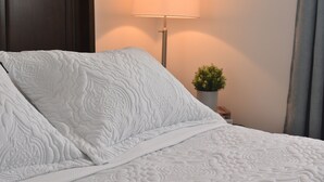 A neatly made bed with a white quilt, a bedside lamp, and a small potted plant. - Waterfront Cottage| Firepit Family Retreat 10mins to DT Huntsville & Deerhurst (Huntsville)