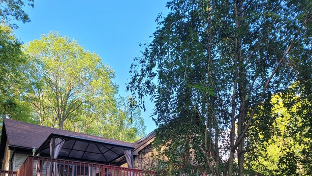 Una casa a due piani con portico coperto, facciata in pietra e giardino.