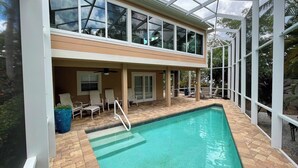 A two-story building with a swimming pool, outdoor seating, and large windows. - License to Chill! Bring Your Boat, Sup or Kayak to this 3 bedroom, 3 bath Waterfront Home - Deep Water Canal, No Bridges. Near golf, shops, restaurants. (Sanibel)