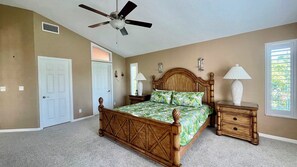 A bedroom with a wooden bed, a ceiling fan, a nightstand, a lamp, and a window with blinds. - License to Chill! Bring Your Boat, Sup or Kayak to this 3 bedroom, 3 bath Waterfront Home - Deep Water Canal, No Bridges. Near golf, shops, restaurants. (Sanibel)