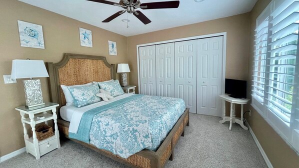 A bedroom with a bed, nightstands, a ceiling fan, a wardrobe, and a TV.