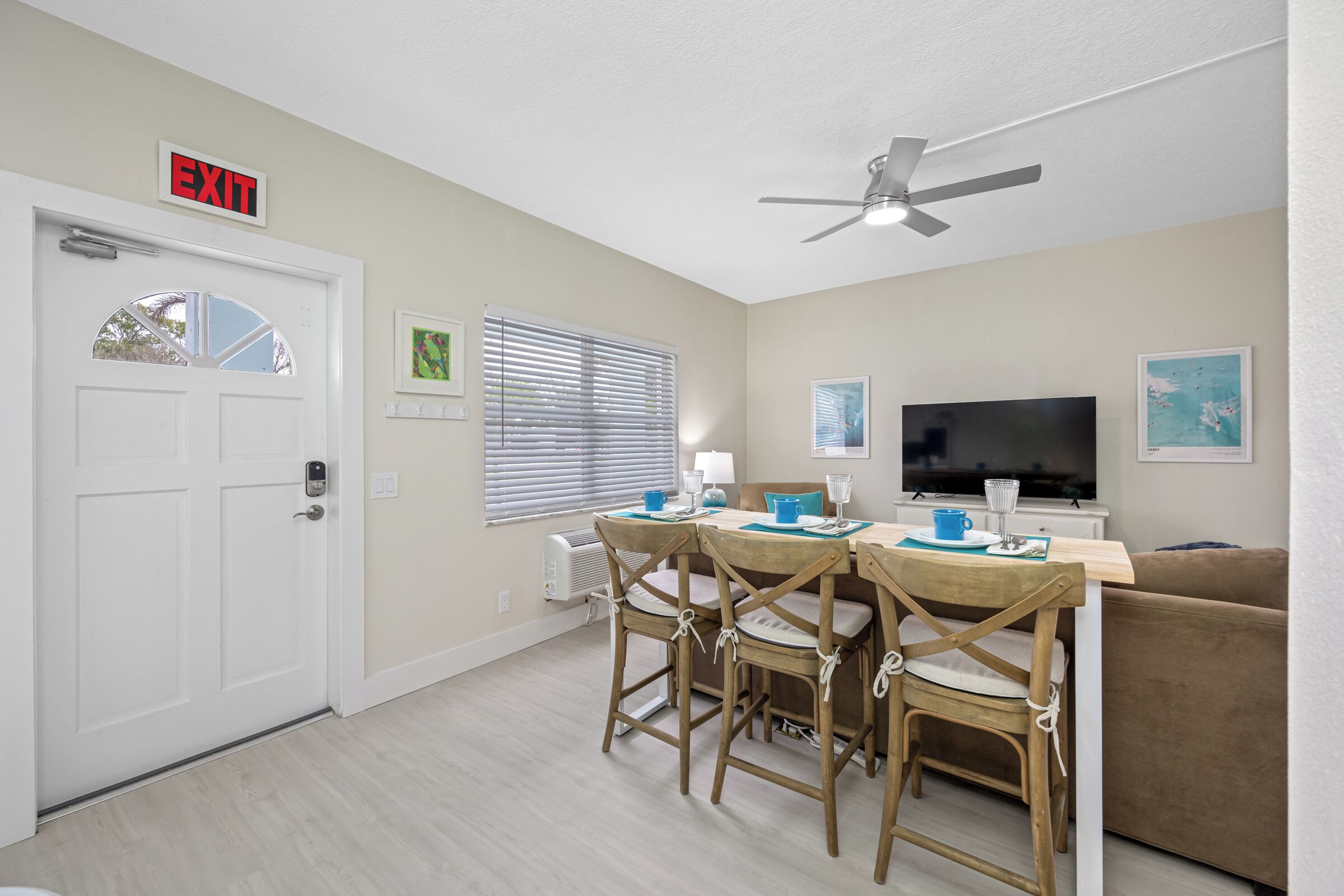 A compact living space with a dining area, a sofa, a TV, and an exit sign.