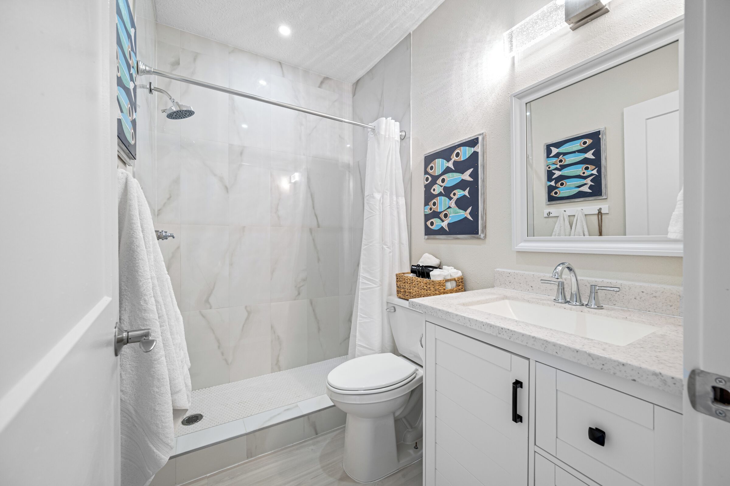 Une salle de bain moderne avec une douche à parois de verre, des toilettes blanches et un lavabo avec un miroir au-dessus.