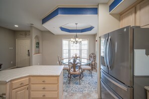A kitchen with a central island, a refrigerator, and a chandelier.