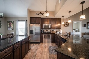 Enjoy cooking in this well-equipped kitchen with a central island, stainless steel appliances, and dark cabinetry.