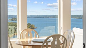 A dining area with a table and chairs, overlooking a large body of water and distant hills. - Lakeview Penthouse 4BR/4BA Condo • Sleeps 12 • Sunroom + Balcony (Branson)
