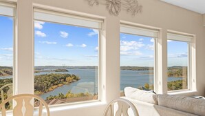 A room with large windows offering a view of a lake and surrounding landscape. - Lakeview Penthouse 4BR/4BA Condo • Sleeps 12 • Sunroom + Balcony (Branson)
