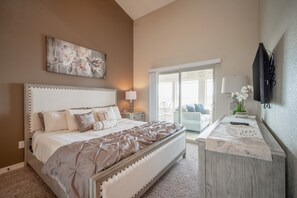 Relax in a spacious bedroom with a large bed, tufted headboard, and contemporary artwork.