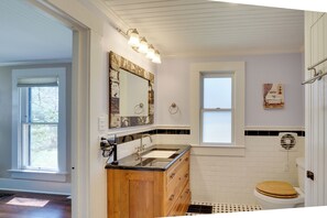 Un baño con tocador de madera, un espejo grande y un inodoro blanco.