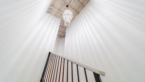 Eine Treppe mit weißer Geländer und Decke mit Holzbalken und einer hängenden Leuchte.
