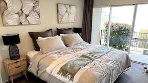 Un dormitorio amplio con una cama grande, una mesita de noche y un ventanal con vistas.