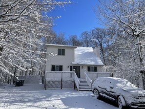A two-story house with a covered porch and a staircase leading to the front door.