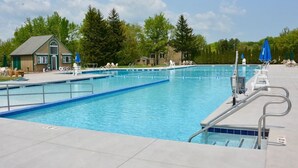 Ein rechteckiger Pool mit klarem, blauem Wasser, umgeben von Liegestühlen und Sonnenschirmen.