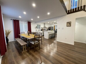 A modern kitchen with a central island, wooden flooring, and a dining area with a bench and chairs.