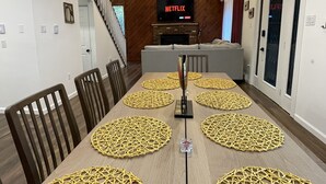 Ein Essbereich mit einem langen Tisch, Stühlen und einem Fernseher, der 'NETFLIX' anzeigt.