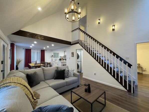 A spacious living area with a large sofa, a coffee table, and a staircase.