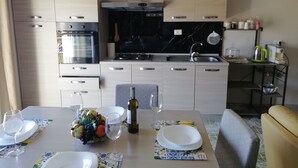 Une cuisine moderne dotée d’appareils électroménagers en acier inoxydable, d’un pare-feu en marbre noir et de meubles de cuisine en bois clair.
