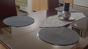 A modern kitchen with a dining table, chairs, a refrigerator, and a window with blinds. - Ginjals_67 (Almargem do Bispo)