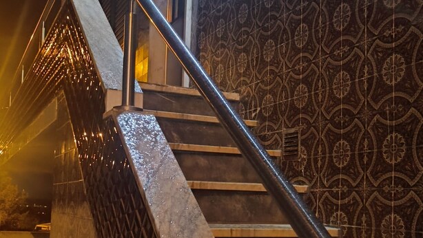 A staircase with a metal handrail, patterned wall tiles, and a light fixture. - Ginjals_67 (Almargem do Bispo)