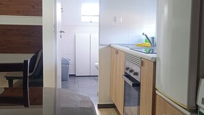 A modern kitchen with a wooden dining table, cabinets, and a refrigerator. - Ginjals_67 (Almargem do Bispo)