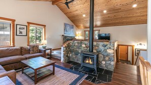 A cozy living room with a stone fireplace, wooden ceiling, and a comfortable sofa.