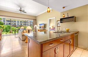 A modern kitchen with a large island, a dining area with a view, and a ceiling fan.