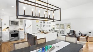Eine moderne Küche mit weißen Schränken, einem Edelstahlbackofen und einem Essbereich mit dunklem Tisch und Stühlen.