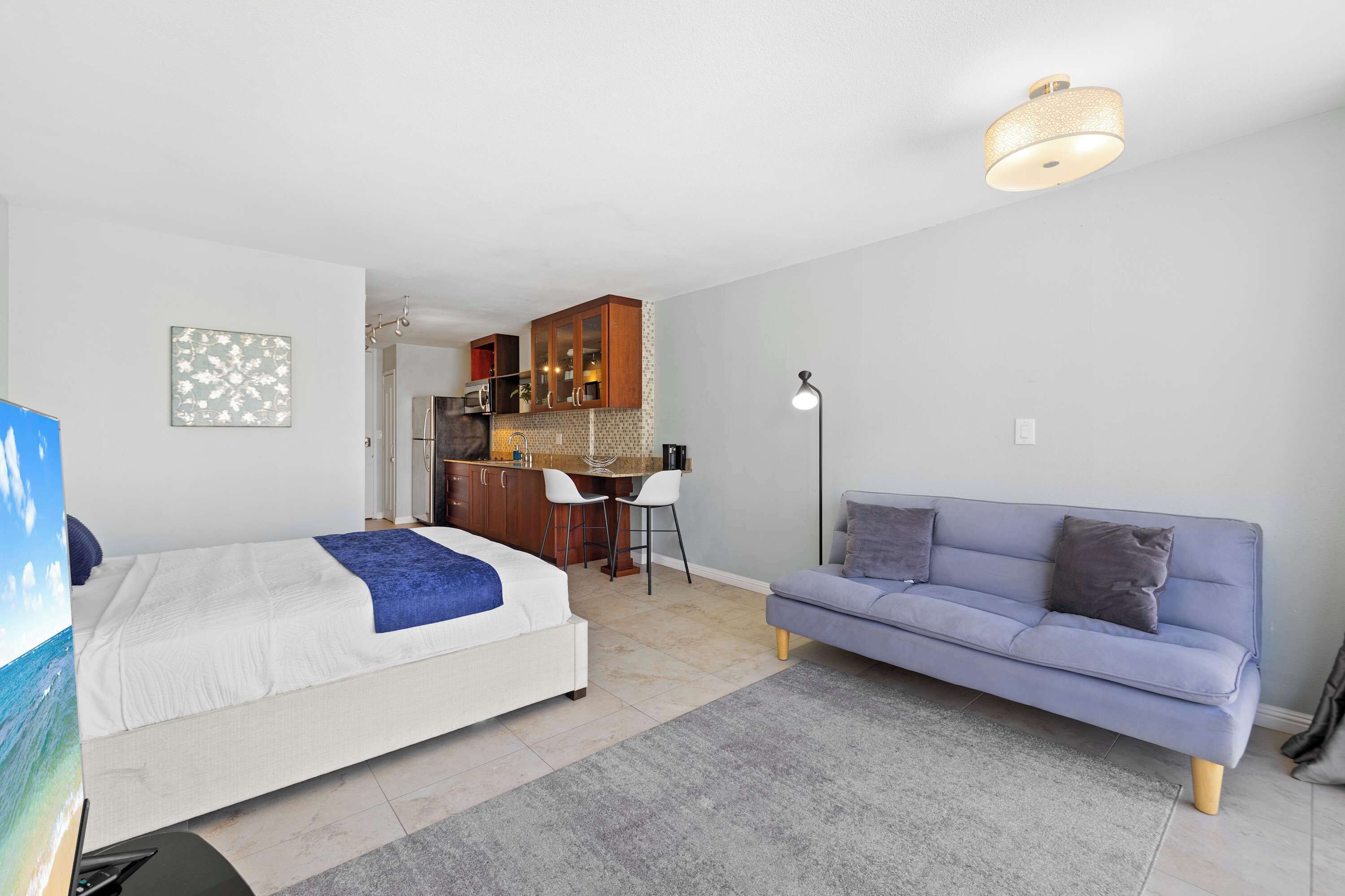 Une chambre comprenant un lit, un canapé, un bureau et un coin cuisine.
