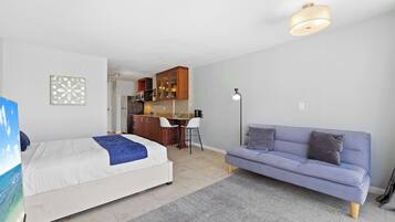 Une chambre comprenant un lit, un canapé, un bureau et un coin cuisine.
